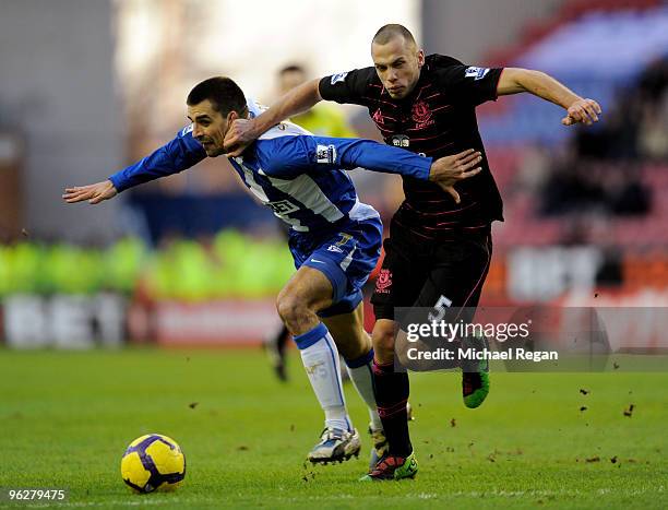 John Heitinga of Everton tangles with Paul Scharner of Wigan during the Barclays Premier League match between Wigan Athletic and Everton at the DW...