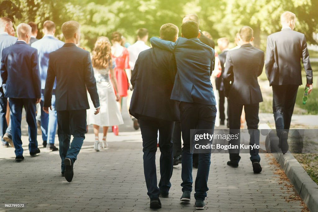Stylish confident man in suit having fun, group of people walking, reception at luxury wedding, rich graduation at school or university