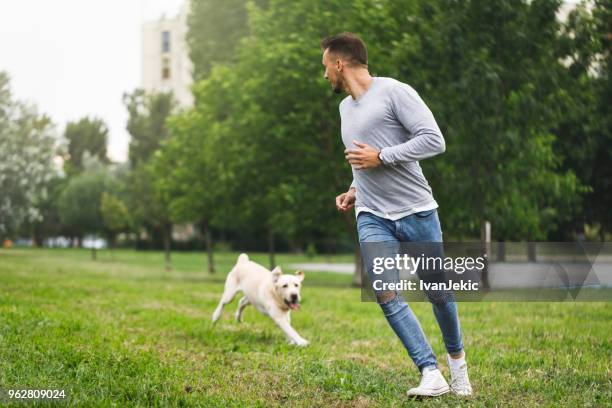 dog running with his owner - ivanjekic stock pictures, royalty-free photos & images