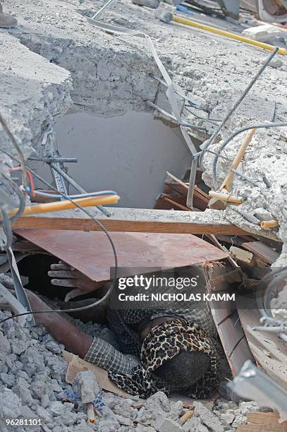 Man trapped in the tax authority building moves a board away in Port-au-Prince on January 14 two days after an earthquake measuring 7.0 on the...