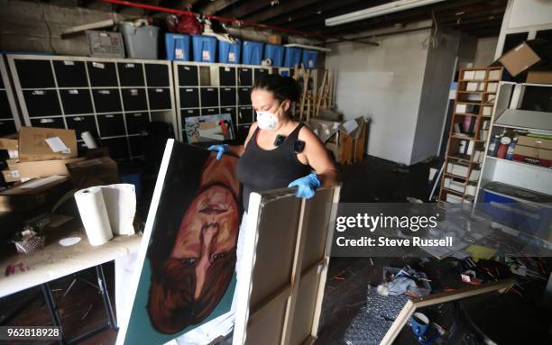 Ilene Sova carries out pieces of her art to be assessed and cleaned. Walnut Studios, a west end building that housed 44 artist studios suffered a...