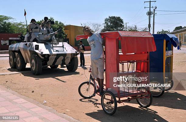 Young man stands on his tricicle next to Colombian soldiers during a meeting between the army and villagers of the town of Uribia, in La Guajira...