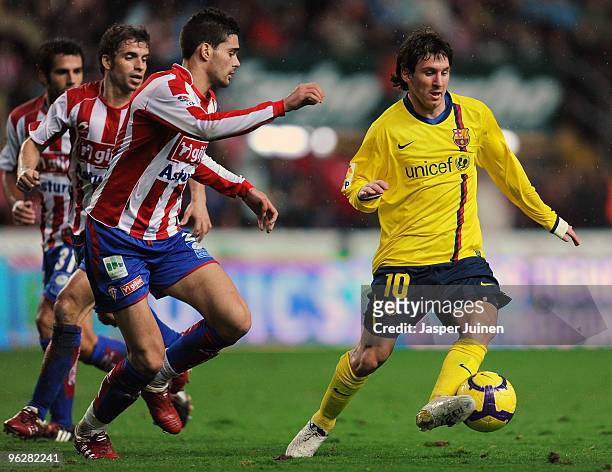 Lionel Messi of FC Barcelona duels for the ball with Alberto Botia of Sporting Gijon during the La Liga match between Sporting Gijon and Barcelona at...