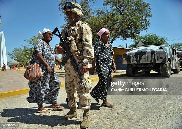 Colombia's Wayuu indigenous women walk next to a Colombian soldier during a meeting between the army and villagers of the town of Uribia, in La...