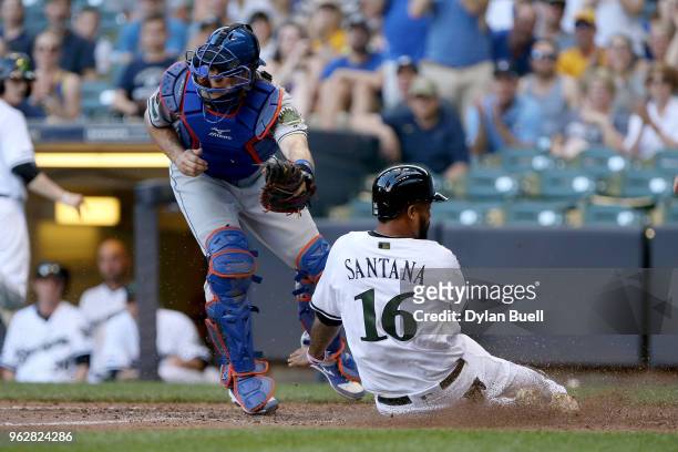 Domingo Santana of the Milwaukee Brewers slides into home plate to score a run past Devin Mesoraco of the New York Mets in the seventh inning at...