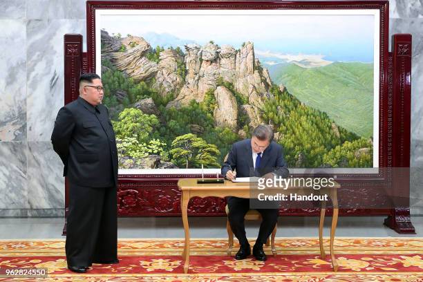 In this handout image provided by South Korean Presidential Blue House, South Korean President Moon Jae-In signs his name as North Korean leader Kim...