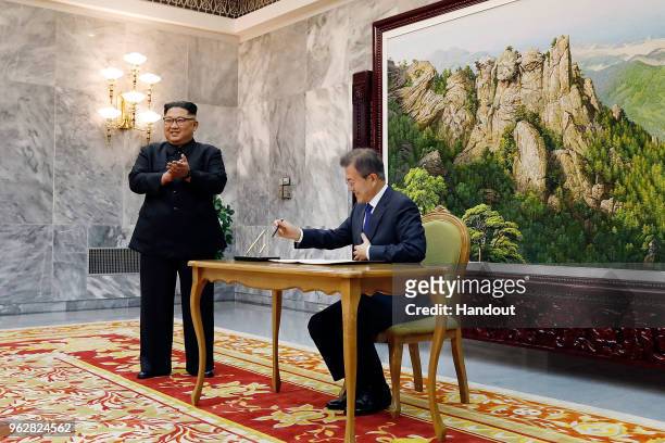 In this handout image provided by South Korean Presidential Blue House, South Korean President Moon Jae-In signs his name as North Korean leader Kim...