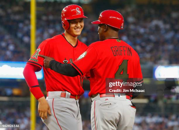 Shohei Ohtani of the Los Angeles Angels of Anaheim has a laugh with first base coach Alfredo Griffin after drawing a bases loaded walk during the...