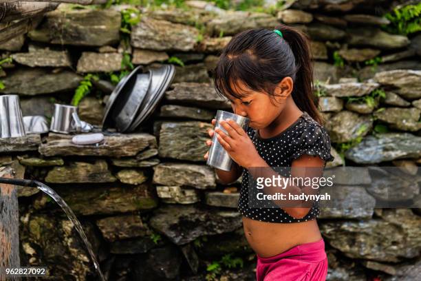 nepalees meisje drinkwater, dorp in de buurt van annapurna bereik - annapurna circuit stockfoto's en -beelden