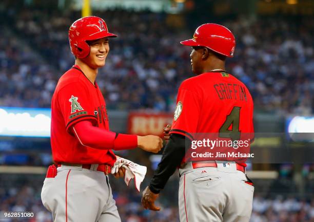 Shohei Ohtani of the Los Angeles Angels of Anaheim has a laugh with first base coach Alfredo Griffin after drawing a bases loaded walk during the...