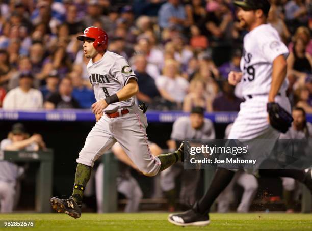 Jose Peraza of the Cincinnati Reds scores on a wild pitch from Bryan Shaw of the Colorado Rockies, right, in the seventh inning at Coors Field on May...
