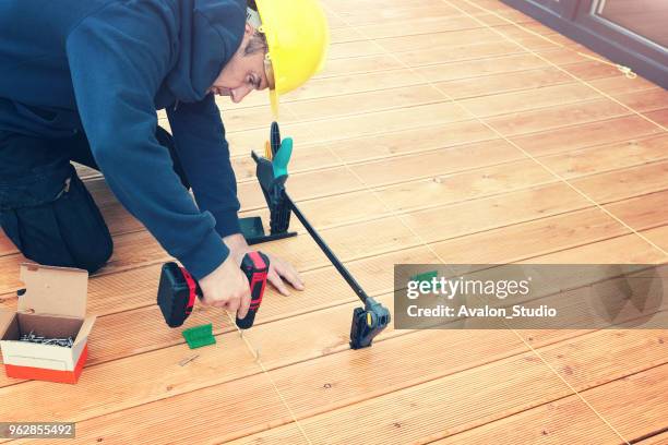 construction worker screwing down wood deck with battery power screw gun or drill. - building decking stock pictures, royalty-free photos & images