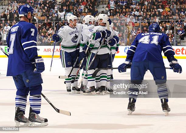 Ian White and Nikolai Kulemin of the Toronto Maple Leafs skate past as the Vancouver Canucks celebrate a third period goal during game action January...