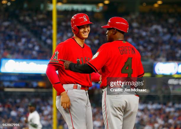 Shohei Ohtani of the Los Angeles Angels of Anaheim has a laugh with first base coach Alfredo Griffin after drawing a bases loaded walk during the...