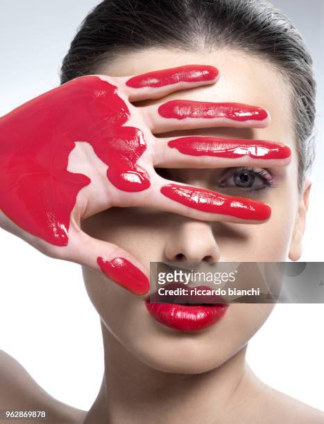 beautiful woman with red lips and one hand dirty with red paint - raster stock-fotos und bilder