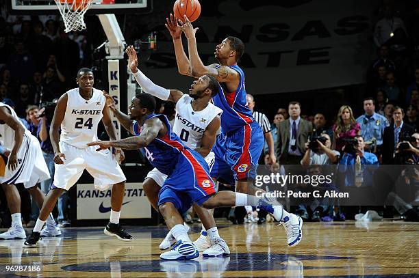 Forward Marcus Morris of the Kansas Jayhawks reaches for a loose ball with guard Jacob Pullen of the Kansas State Wildcats and teammate Sherron...