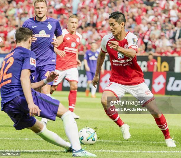 Mainz's Yoshinori Muto tries to break away from Werder Bremen's Marco Friedl during a match in Mainz, Germany, on May 12, 2018. Werder Bremen won...