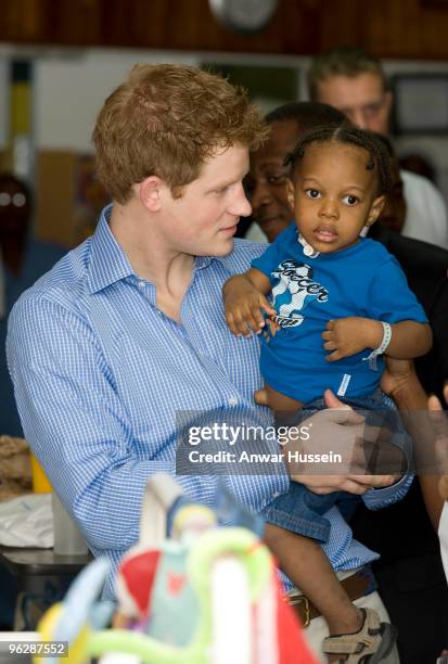 Prince Harry holds young patient Tyrell Richards when he visits the childrens ward at the Queen Elizabeth ll hospital on January 30, 2010 in...