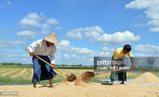 Workers spread paddy on plastic sheet to dry under the sun at a rice mill in Naypyidaw on May 27, 2018.