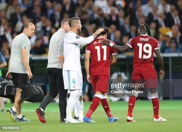 Liverpool's Egyptian forward Mohamed Salah is comforted by team members and Real Madrid's Sergio Ramos as he leaves the pitch after injury during the...