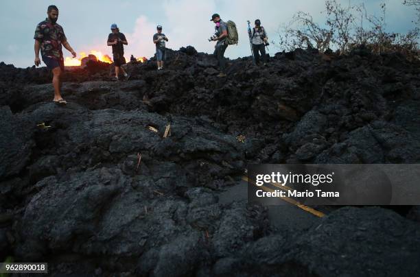 Onlookers and photographers walk on hardened lava from a Kilauea volcano fissure as lava erupts in Leilani Estates, on Hawaii's Big Island, on May...