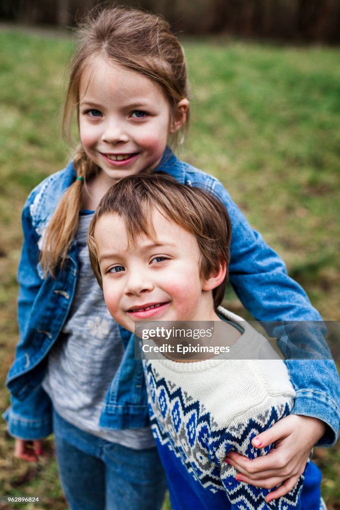 Portrait d’une fille souriante avec un frère debout sur le terrain