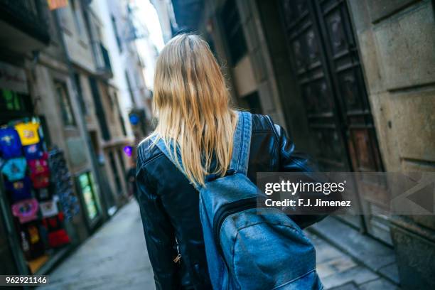 woman with backpack walking down the street - woman walks down street stock pictures, royalty-free photos & images