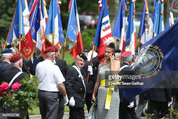 Woman wearing a flowery headdress talks on a mobile phone as French standard bearers file past following a ceremony to commemorate the 100th...