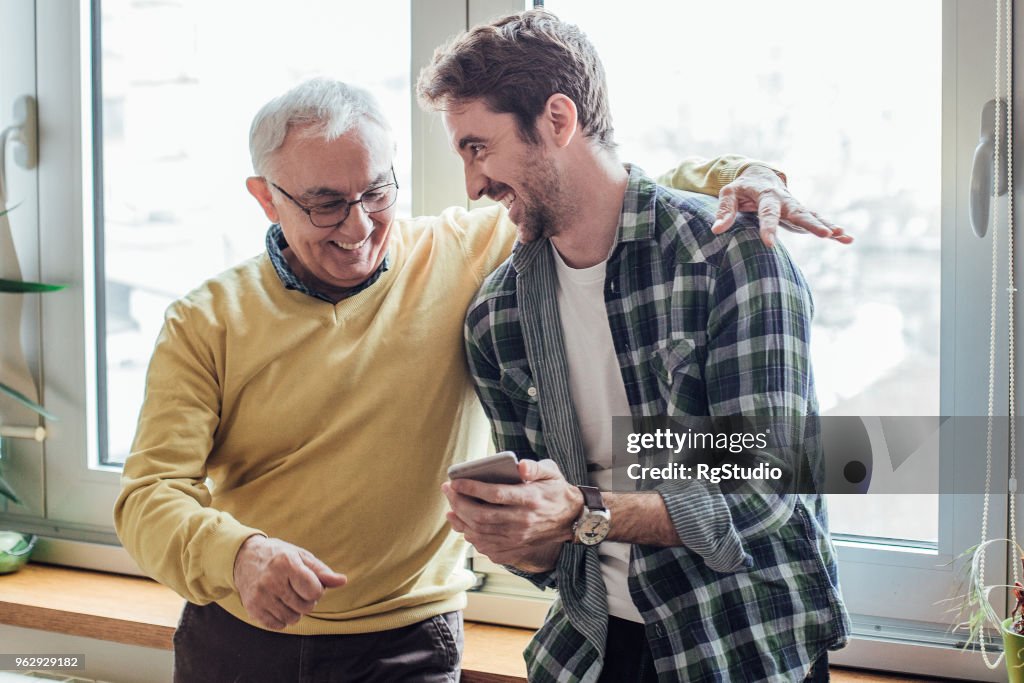 Vater und Sohn lachend und mit Telefon