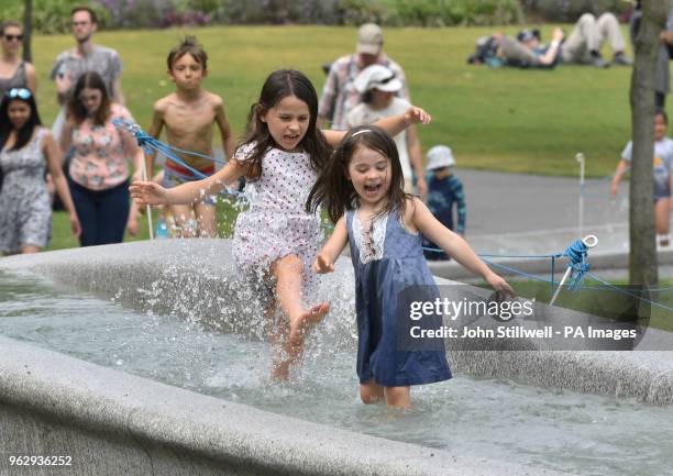Children cool off in the Diana Memorial Fountain in Hyde Park, London.