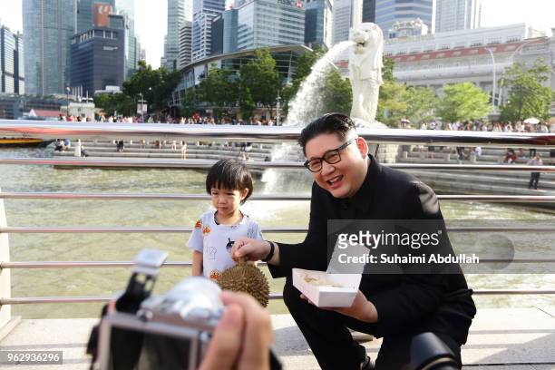 Kim Jong Un impersonator, Howard X poses for a photo with a young kid at Merlion Park on May 27, 2018 in Singapore. The proposed North Korea-United...