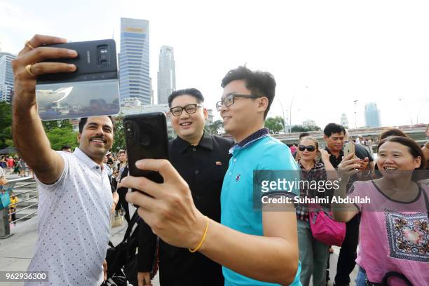 Kim Jong Un impersonator, Howard X poses for a photo with tourists at Merlion Park on May 27, 2018 in Singapore. The proposed North Korea-United...
