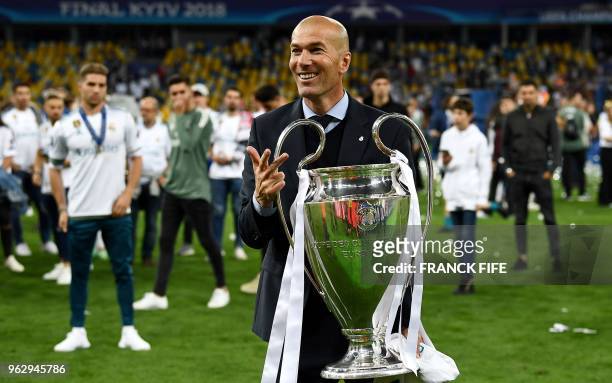 Real Madrid's French coach Zinedine Zidane gestures the number three and holds the trophy as he celebrates winning the UEFA Champions League final...