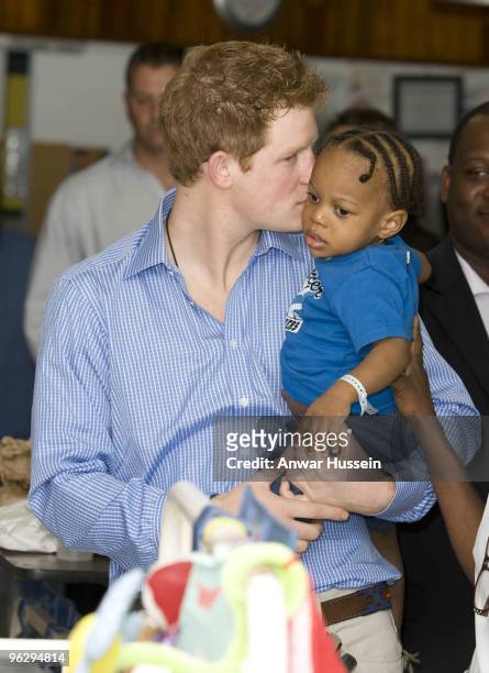 Prince Harry kisses young patient Tyrell Richards when he visits the childrens ward at the Queen Elizabeth ll hospital on January 30, 2010 in...