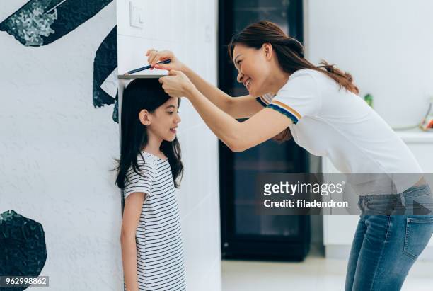 madre che misura l'altezza di sua figlia - height foto e immagini stock