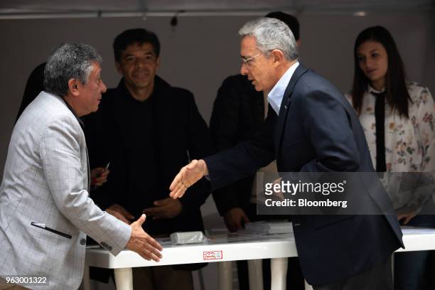 Alvaro Uribe, former president of Colombia, center, extends his hand to a polling official while arriving to cast his ballot at the National Congress...