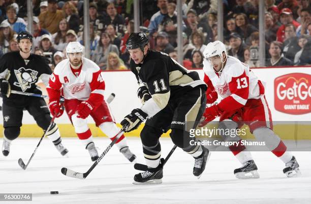Jordan Staal of the Pittsburgh Penguins moves the puck up ice in front of Henrik Zetterberg and Pavel Datsyuk of the Detroit Red Wings on January 31,...