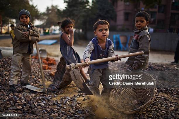 Indian children work nearby to their parents at a construction project in front of the Jawaharlal Nehru Stadium on January 30, 2010 in New Delhi,...