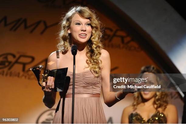 Singer Taylor Swift accepts an award as singer Colbie Caillat stands in the back during the 52nd Annual GRAMMY Awards pre-telecast held at Staples...