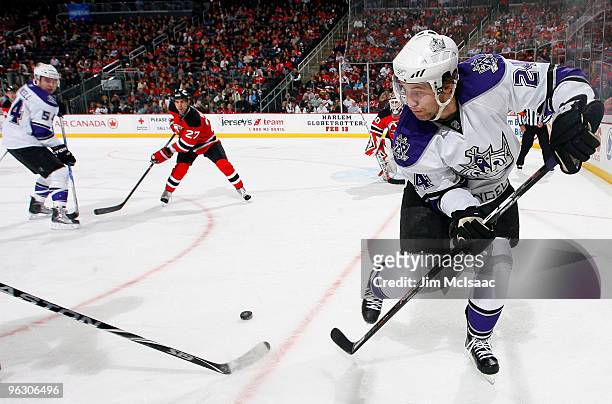 Alexander Frolov of the Los Angeles Kings passes the puck to teammate Teddy Purcell as Mike Mottau of the New Jersey Devils looks on at the...