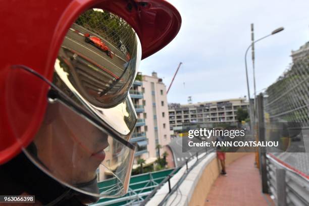 Ferrari's German driver Sebastian Vettel is refelcted into a firefighter's protective mask as he competes during the Monaco Formula 1 Grand Prix at...