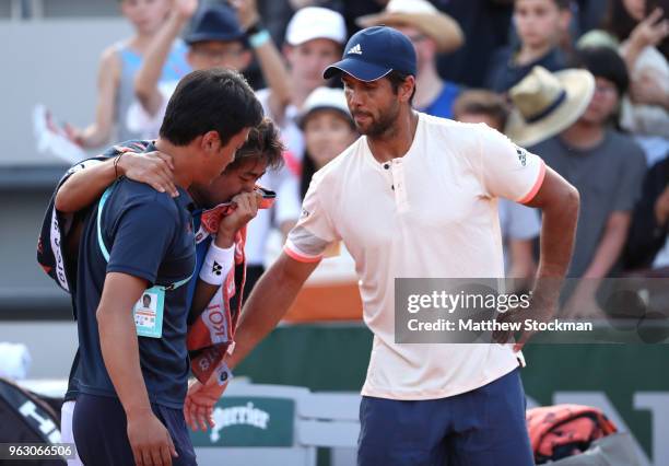 Yoshihito Nishioka of Japan shows his emotions as he is helped off the court following an injury in his mens singles first round match against...