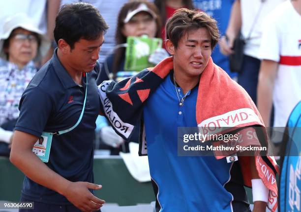 Yoshihito Nishioka of Japan shows his emotions as he is helped off the court following an injury in his mens singles first round match against...