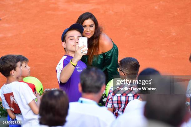 Former player Marion Bartoli, who now does on court interviews, poses for a selfie with a fan during Day 1 of the the French Open at Roland Garros on...