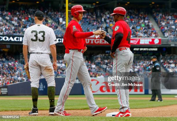 Shohei Ohtani of the Los Angeles Angels of Anaheim fist bumps first base coach Alfredo Griffin after drawing a walk in the ninth inning as Greg Bird...