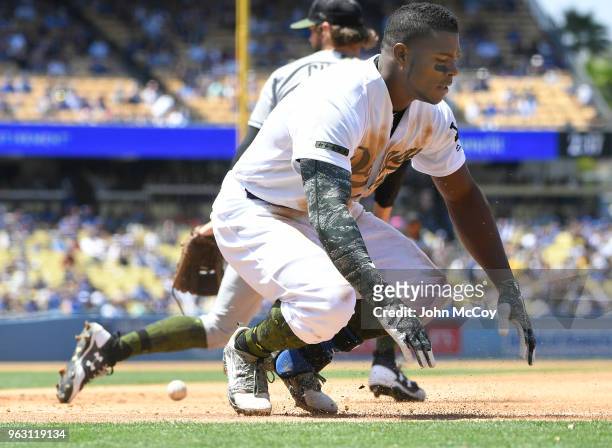 Yasiel Puig of the Los Angeles Dodgers is safe at first base when pitcher Adam Cimber of the San Diego Padres droped the ball at Dodger Stadium on...