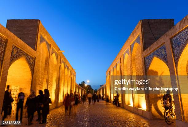 people walking on a bridge at night - isfahan stock pictures, royalty-free photos & images