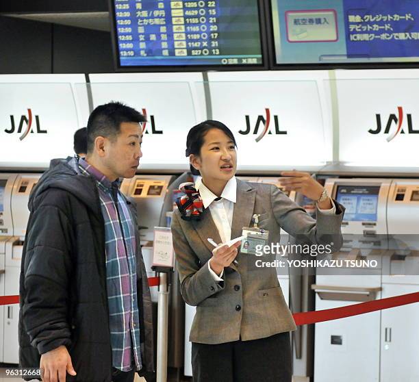 In a picture taken on January 29, 2010 an employee of Asia's largest air carrier Japan Airlines guides a passenger at Tokyo's Haneda airport. A...