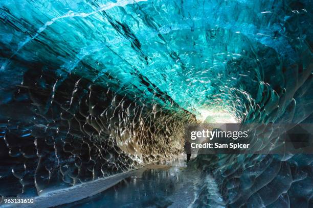 tourist in crystal ice cave, iceland - vatnajokull photos et images de collection
