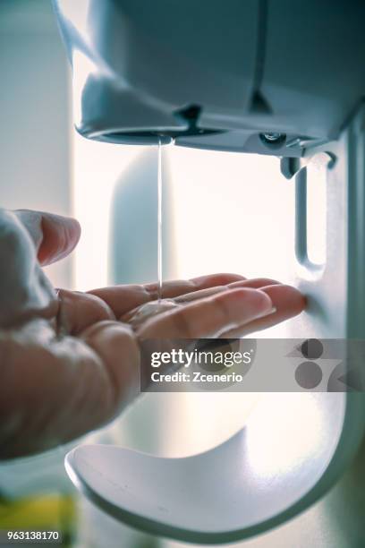 hand cleaning after touching infectious waste using automatic dispenser alcohol cleansing gel - saline bottle stock pictures, royalty-free photos & images